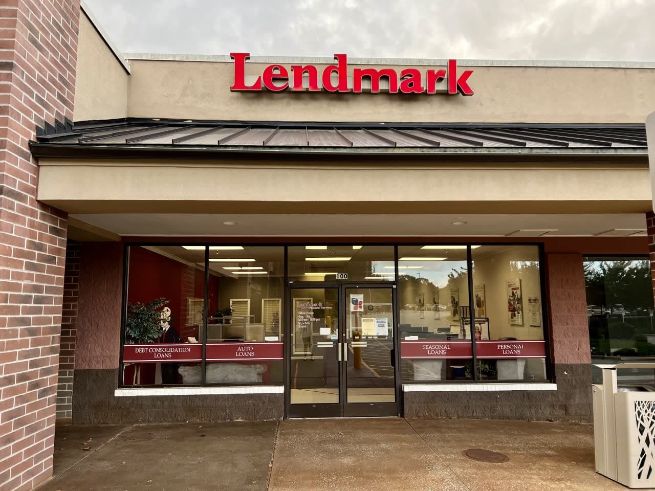 A storefront with large windows and a red "Lendmark" sign above. Loan types like "Auto" and "Personal" are displayed. The setting is clean and inviting.